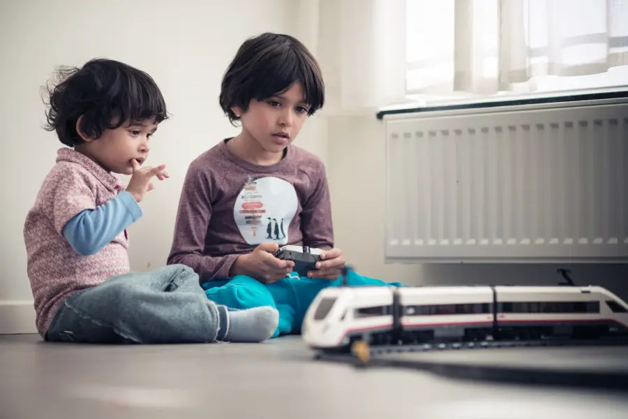 dos niños sentados jugando con un tren eléctrico