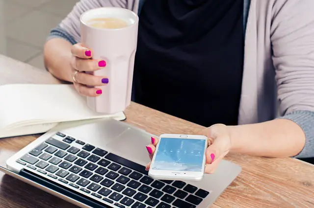 mujer trabajando en computadora con cafe en la mano