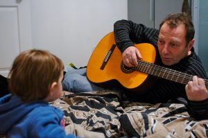 padre tocando la guitarra para su hijo