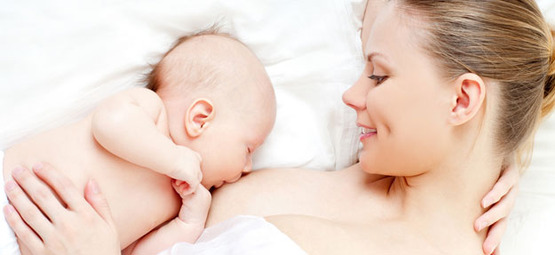 Mujer de costado amamantando a un bebé