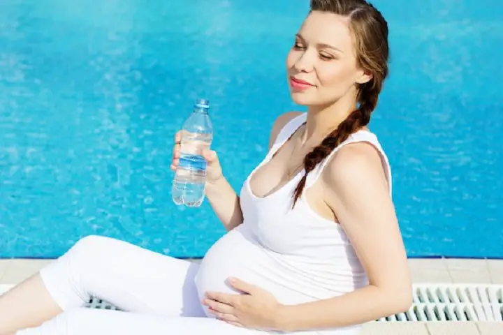 Mujer embarazada sentada en la orilla de una piscina