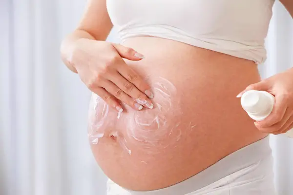 Foto de mujer embarazada aplicando crema en su panza
