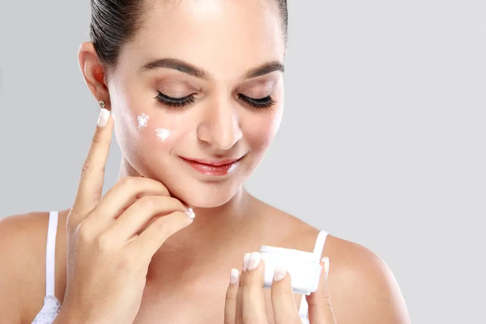 mujer aplicando crema a su rostro